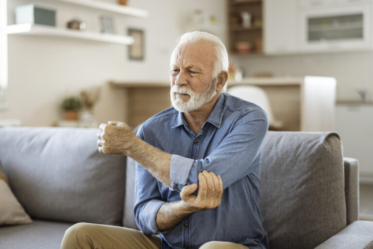 Man holding his elbow experiencing arthritis.