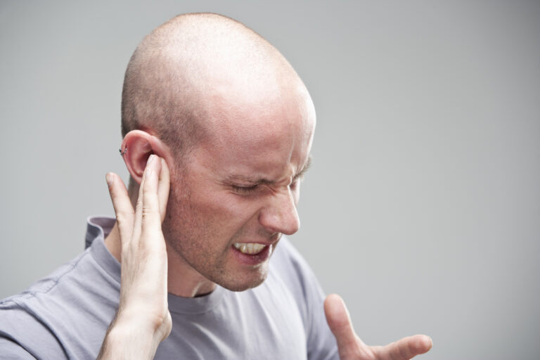 Man suffering from hearing loss holding his ear. 