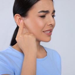 Woman with muffled hearing pointing to her ear
