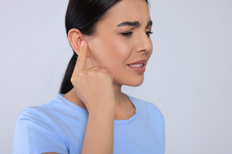 Woman with muffled hearing pointing to her ear