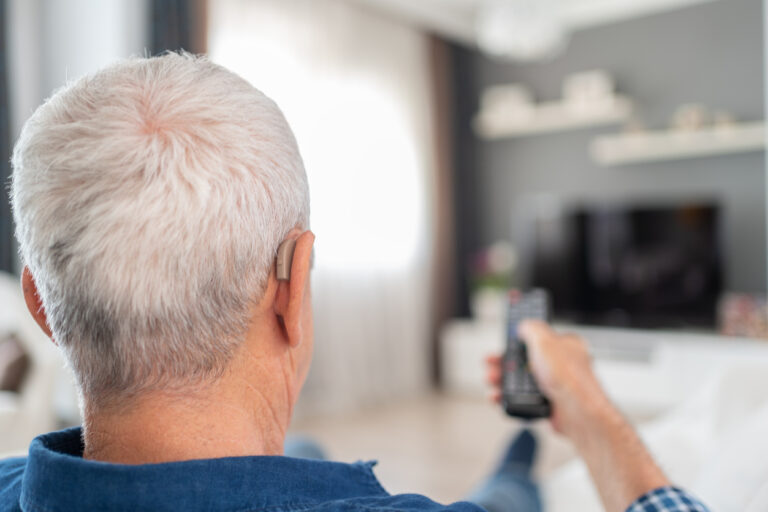 Man with a hearing aid sitting down to watch tv