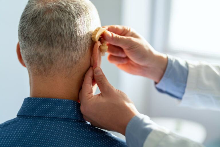 Audiologist fitting a hearing aid on a patient