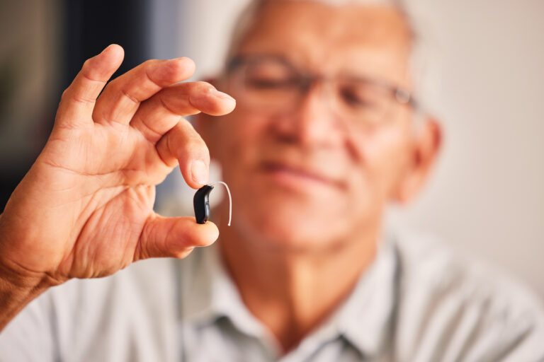 Older man holds hearing aids